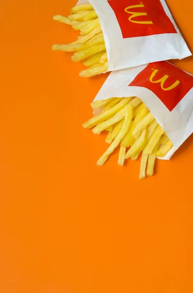 Batatas fritas McDonald 's em pequeno saco de papel sobre fundo laranja brilhante — Fotografia de Stock