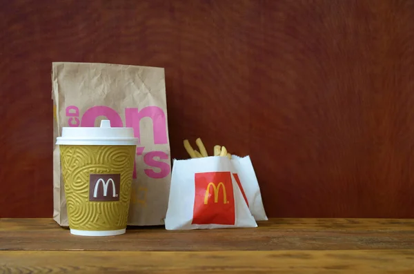 McDonald's take away paper bag and junk food on wooden table — Stock Photo, Image