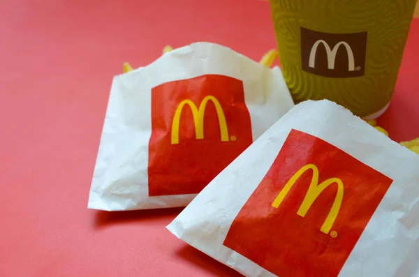 Hranolky na MacDonaldovy hranolky v malém sáčku a kávovém šálku na jasně červeném pozadí — Stock fotografie