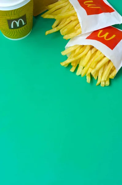 Pommes frites von mcdonald in kleiner Papiertüte und Kaffeetasse auf hellgrünem Hintergrund — Stockfoto
