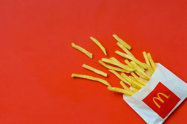 Patatas fritas McDonald 's en una pequeña bolsa de papel sobre fondo rojo brillante —  Fotos de Stock