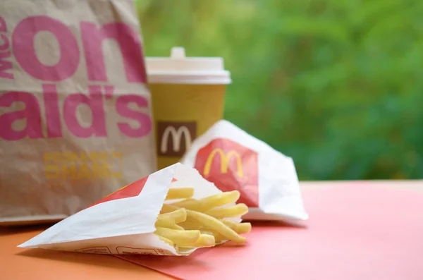 Mcdonald 's zum Mitnehmen Papiertüte und Junk Food auf Holztisch im Freien — Stockfoto