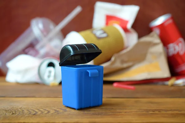Toy garbage bin and McDonald's disposable trash on dark brown wooden background — Stock Image Toy garbage bin and McDonald's disposable trash on dark brown wooden background Stock Photo