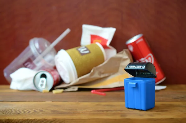 Toy garbage bin and McDonald's disposable trash on dark brown wooden background — Stock Image Toy garbage bin and McDonald's disposable trash on dark brown wooden background Royalty Free Stock Images
