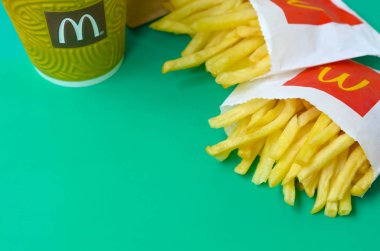 Parlak yeşil arka plan üzerinde küçük paperbag ve kahve fincanı Mcdonald's Patates kızartması