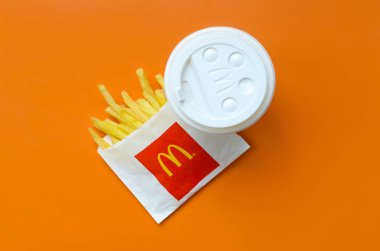 Parlak turuncu arka plan üzerinde küçük paperbag ve kahve fincanı Mcdonald's Patates kızartması