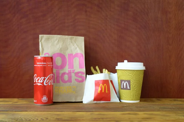 McDonald 's llevar bolsa de papel y papas fritas con cola de coca en una mesa de madera —  Fotos de Stock