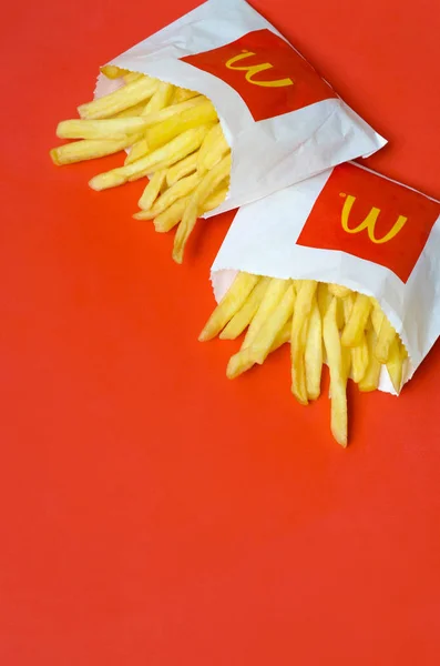 Patatas fritas McDonald 's en una pequeña bolsa de papel sobre fondo rojo brillante —  Fotos de Stock