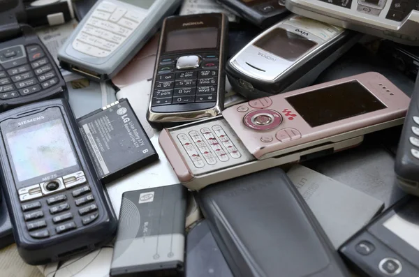 Kilka starych używanych przestarzałych telefonów komórkowych i baterii. Elektronika recyklingowa — Zdjęcie stockowe