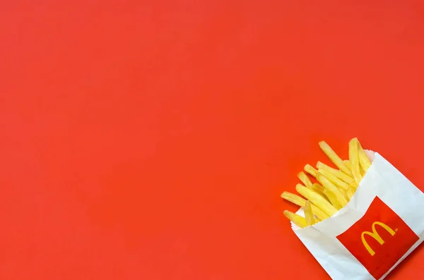 Patatas fritas McDonald 's en una pequeña bolsa de papel sobre fondo rojo brillante —  Fotos de Stock