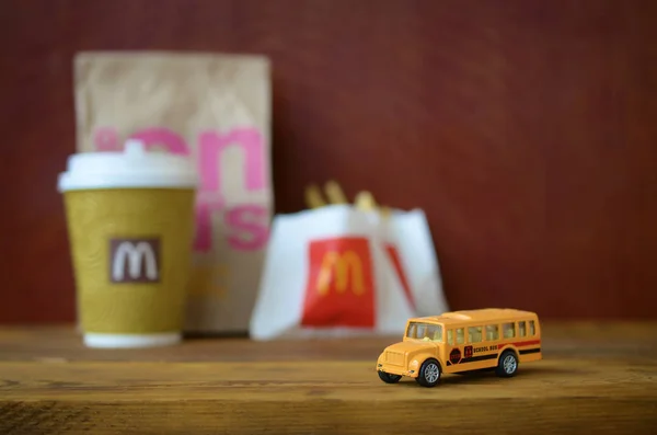 Mały autobus szkolny i Fast food Mcdonald's na drewnianym stole — Zdjęcie stockowe