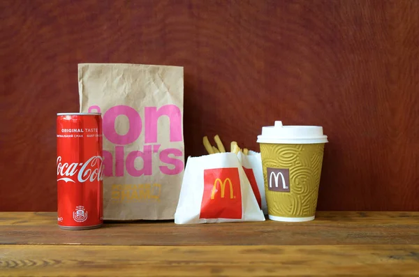 Mcdonald's take-away papieren zak en frietjes met Coca Cola kan op houten tafel — Stockfoto