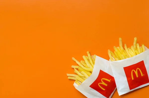 Pommes frites von mcdonald in kleiner Papiertüte auf leuchtend orangefarbenem Hintergrund — Stockfoto