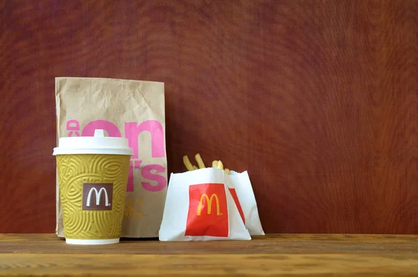 McDonald 's levar saco de papel e junk food na mesa de madeira — Fotografia de Stock