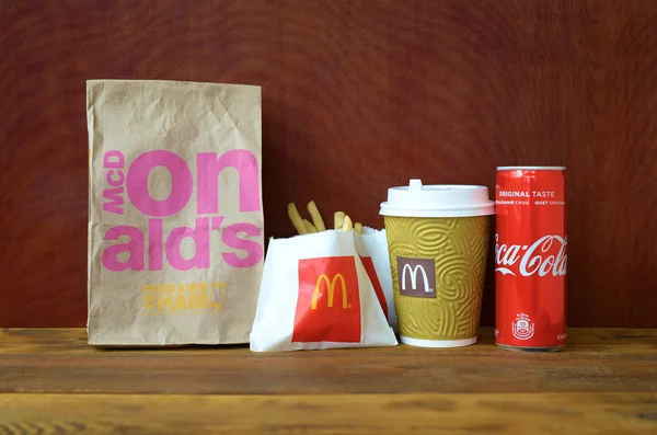 Mcdonald 's zum Mitnehmen Papiertüte und Pommes mit Coca-Cola-Dose auf Holztisch — Stockfoto