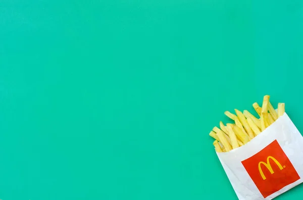 Mcdonald's frietjes in kleine paperbag op heldere groene achtergrond — Stockfoto