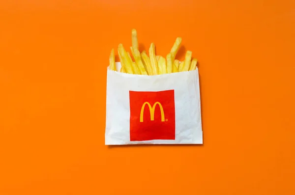 밝은 오렌지 색 배경에 작은 종이 가방에 맥도날드의 감자 튀김 — 스톡 사진