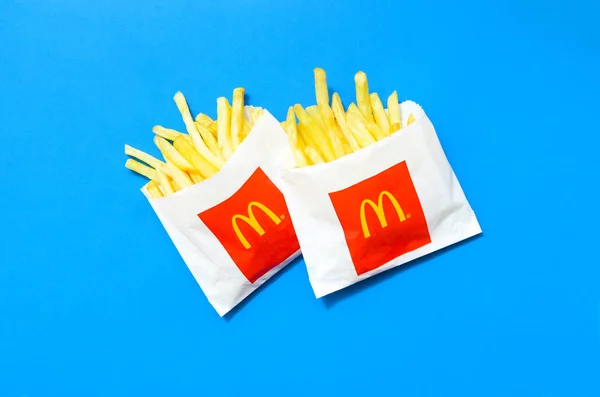 明るい青い背景に小さな紙袋でマクドナルドのフライドポテト — ストック写真