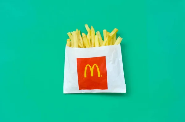 Pommes frites von mcdonald in kleiner Papiertüte auf hellgrünem Hintergrund — Stockfoto