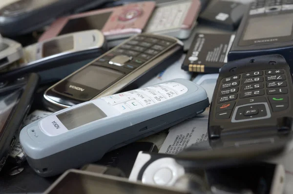 Un montón de viejos teléfonos móviles y baterías anticuados usados. Reciclaje de electrónica — Foto de Stock