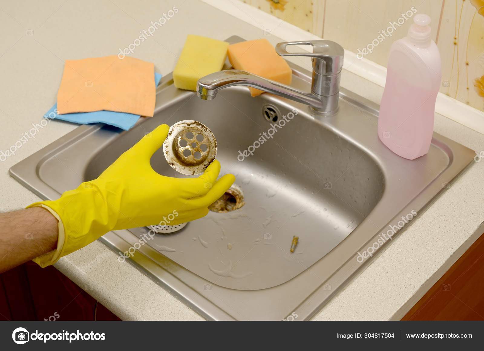 Cleaner in rubber gloves shows waste in the plughole protector of
