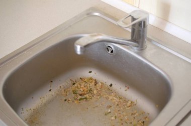 Close up on dirty clogging kitchen sink drain with food particles clipart