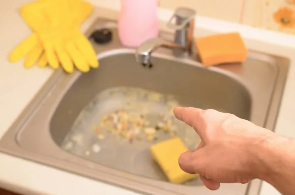 Χέρι σημεία σε βρώμικο νεροχύτη κουζίνα με πολλά σωματίδια τροφίμων πριν από τον καθαρισμό — Φωτογραφία Αρχείου