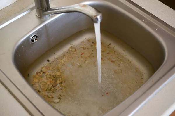 Rozsdamentes acél mosogató dugó lyuk közelről tele a víz és az élelmiszer-részecskék — Stock Fotó