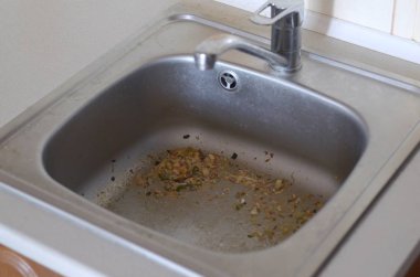 Close up on dirty clogging kitchen sink drain with food particles clipart