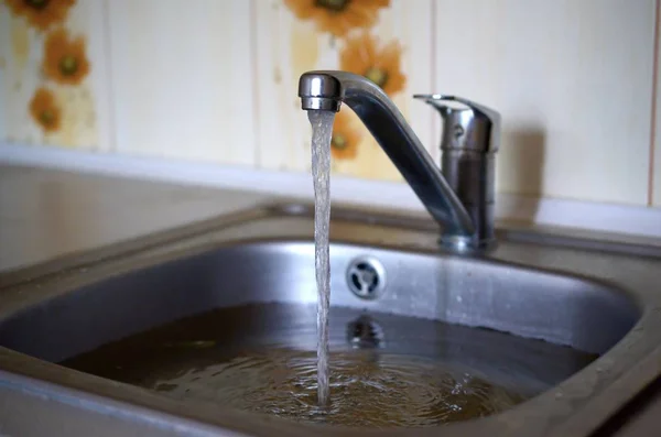 Agujero del fregadero de acero inoxidable primer plano lleno de agua y partículas de comida — Foto de Stock