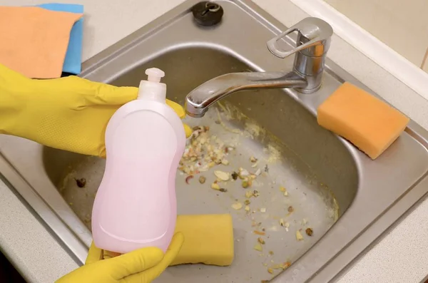 Le nettoyant montre une bouteille de détergent nettoyant liquide à l'évier sale de la cuisine avec des particules de nourriture avant le nettoyage — Photo
