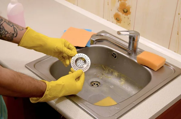 Cleaner in rubber gloves shows clean plughole protector of a kitchen sink — Stock Photo, Image