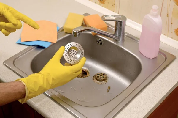 Cleaner in rubberen handschoenen toont schone plug beschermer van een gootsteen — Stockfoto