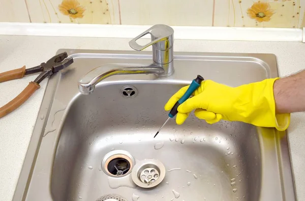 Close-up of handsome plumber hands repairing drain of kitchen sink — Stock Photo, Image