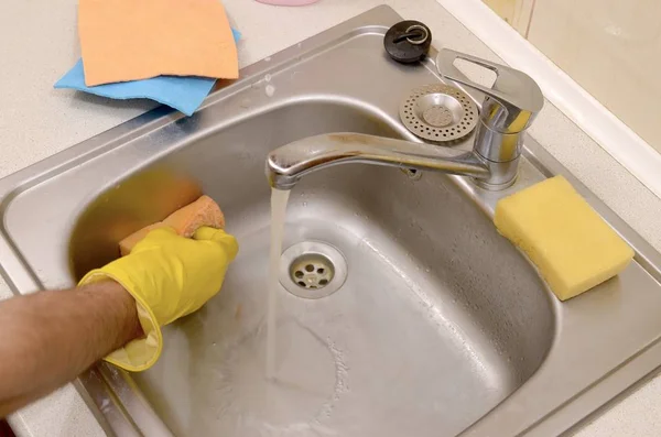 Человек или домовладелец чистят кухонную раковину губкой в поле зрения — стоковое фото
