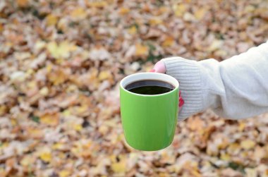 Yeşil kahve fincanı tutan beyaz kazak giyen kadın