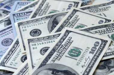 Soyut desenli arka plan ve yüzlerce dolarlık banknotlar.
