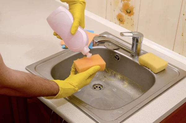 Cleaner applying liquid soap from cleanser detergent bottle to sponge at home