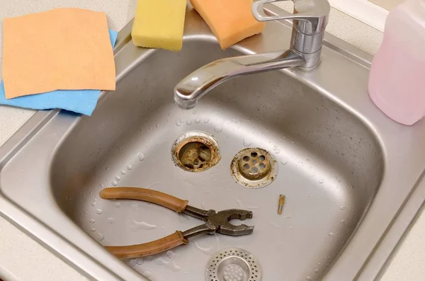 Pliers inside the silvery kitchen sink with a disassembled protective filter — Stock Photo, Image