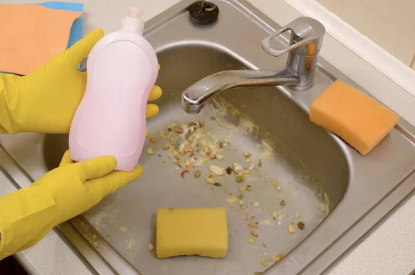 Pembersih menunjukkan botol deterjen pembersih cair di wastafel dapur kotor dengan partikel makanan sebelum pembersihan — Stok Foto