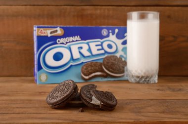 Bir sürü Oreo sandviçi kremalı bisküvi ve tahta arka planda süt bardağı.