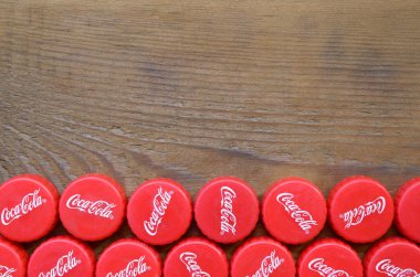 Ahşap zemin üzerinde Coca Cola logosu olan bir sürü kırmızı şapka.