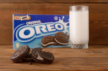 Bir sürü Oreo sandviçi kremalı bisküvi ve tahta arka planda süt bardağı.