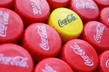 Bir sürü kırmızı kapak ve Coca Cola logolu bir tane de sarı plastik kapak.