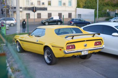 Ford Mustang Mach 1 'in halka açık park yerinde parlak sarı renkli arka planı