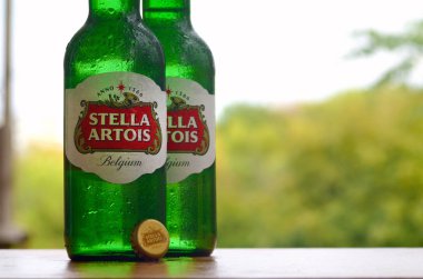 Bulanık yeşil ağaçlarda Stella Artois birası şişeleri