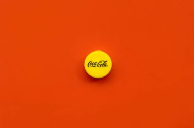 Kırmızı zemin üzerinde Coca Cola logosu olan tek sarı şişe kapağı.