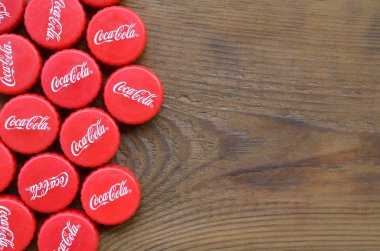 Ahşap zemin üzerinde Coca Cola logosu olan bir sürü kırmızı şapka.