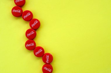 Sarı zemin üzerinde Coca Cola logosu olan bir sürü kırmızı başlık
