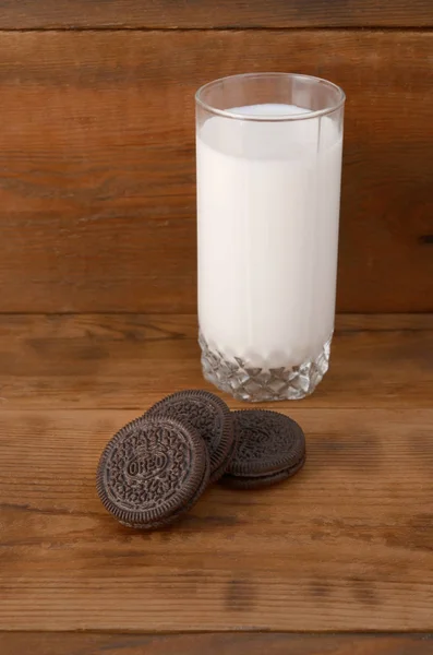 Muchas galletas de crema sandwich OREO y vaso de leche sobre fondo de madera — Foto de Stock